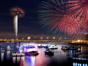 Fireworks firing in the sky and a river below with boats. Fireworks are reflecting off the water | NH on Shutterstock